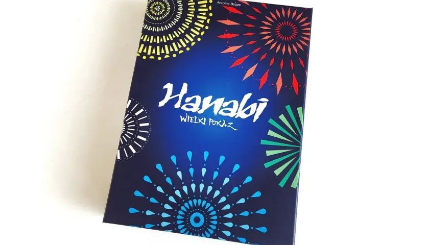 Pudełko gry karcianej Hanabi z kolorowymi fajerwerkami na ciemnoniebieskim tle.