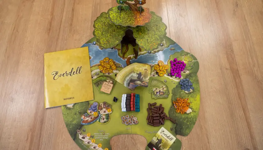 Plansza do gry Everdell z instrukcją i komponentami. Kolorowe zasoby i karty czekają na graczy.