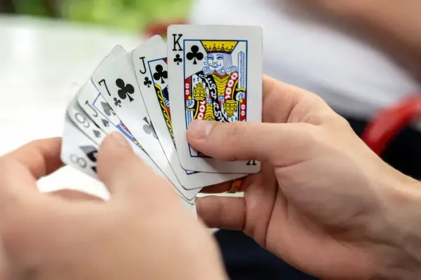 Ręce trzymają karty, w tym króla i waleta. Czy to początek gry, czy oszust gra karciana?